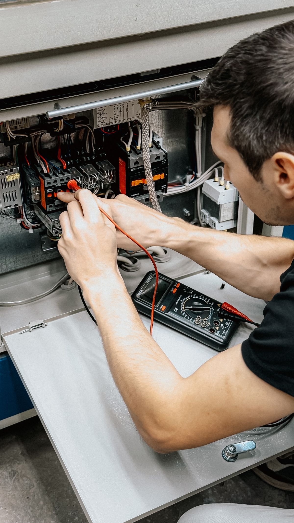 Eletricista verificando um painel elétrico com multímetro
