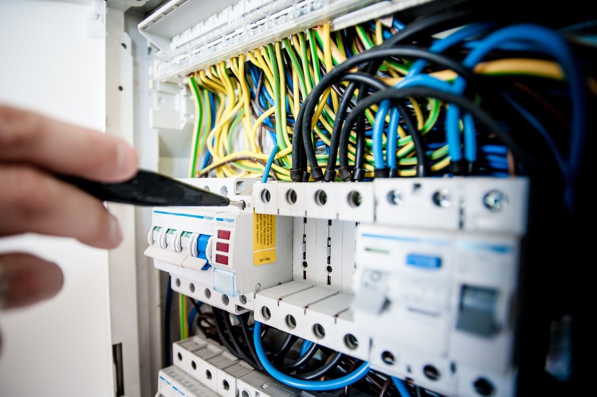 Eletricista trabalhando em um painel durante visita técnica